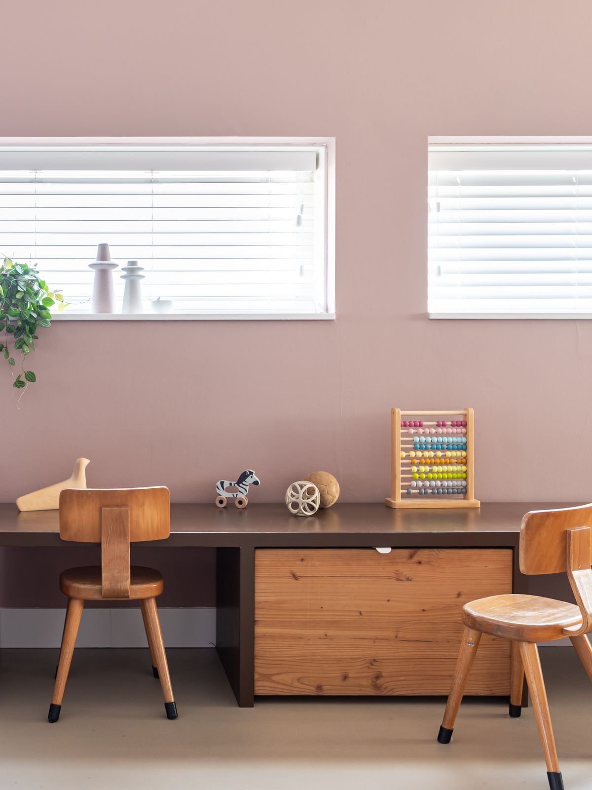 Kinderhoekje met houten bureau, stoeltjes en speelgoed in een warm interieur