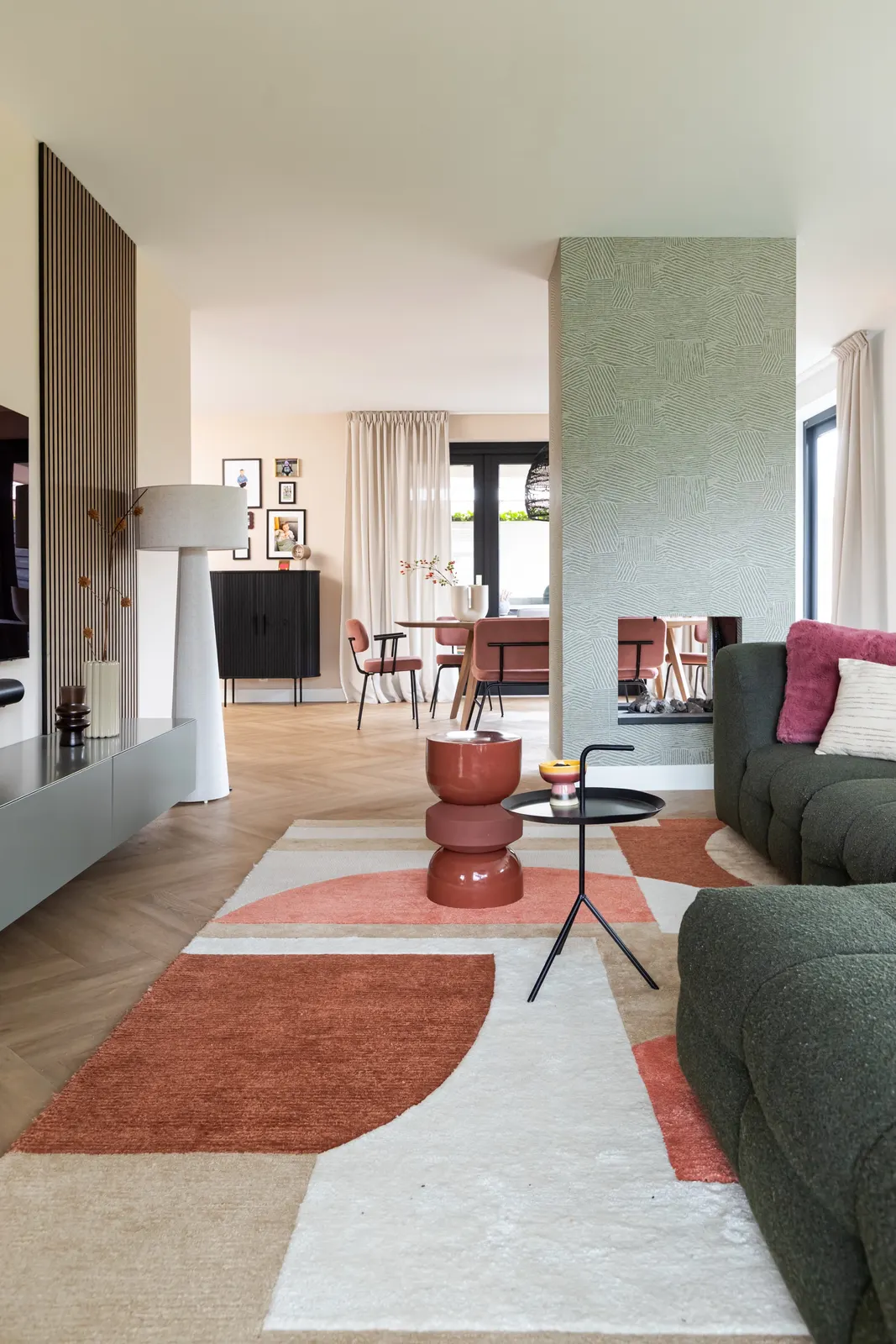 Woonkamer met groene bank en oranje vloerkleed in een villa in Zwolle