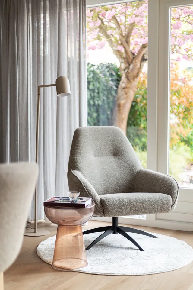 Vloerlamp bij een grijze fauteuil in een lichte woonhoek