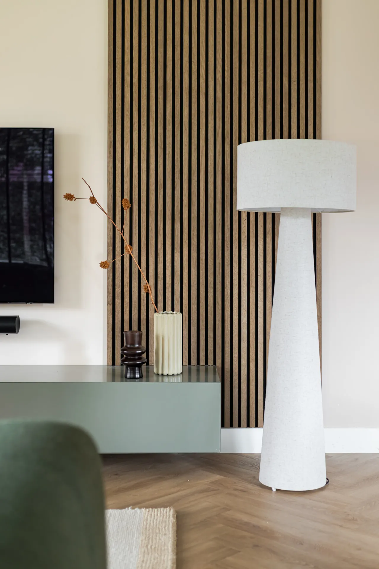 Vloerlamp bij een houten lamellenwand en een groen zwevend dressoir in Zwolle