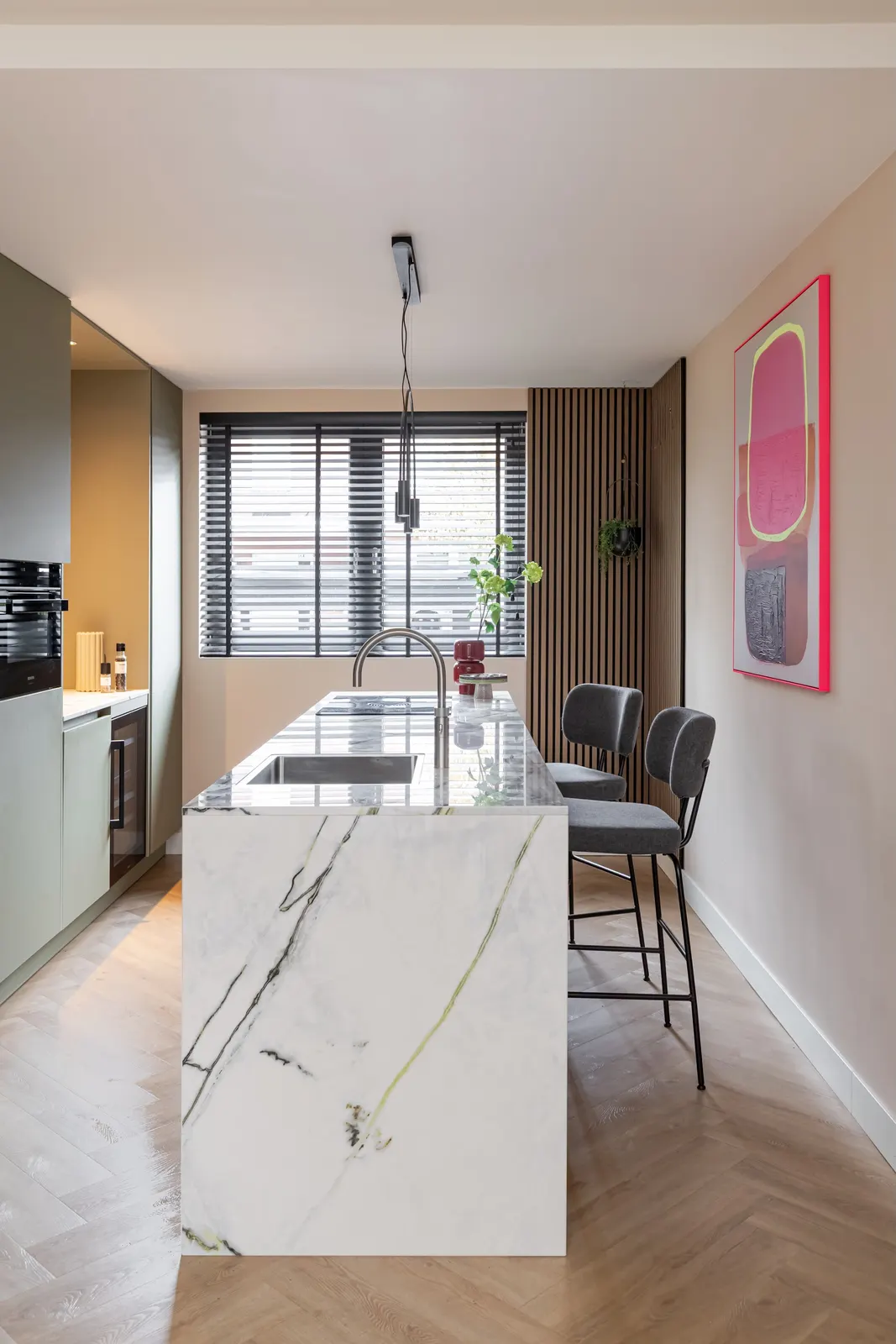Keuken met marmeren kookeiland en kleurrijk kunstwerk in een villa in Zwolle