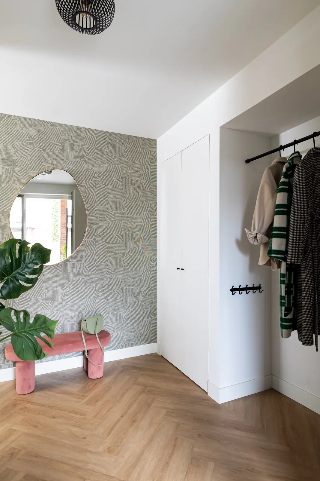 Hal met structuurbehang, ronde spiegel en kapstok in een villa in Zwolle