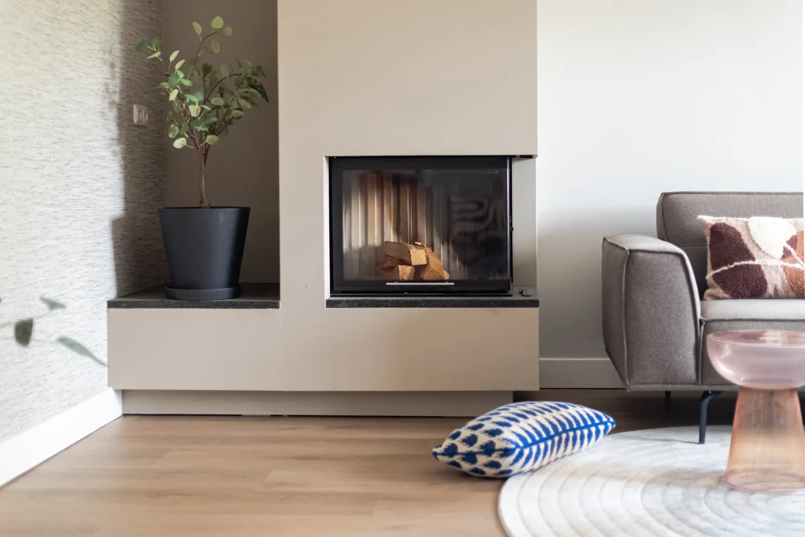 Open haard met brandend hout en blauw kussen in hoekwoning Zwolle