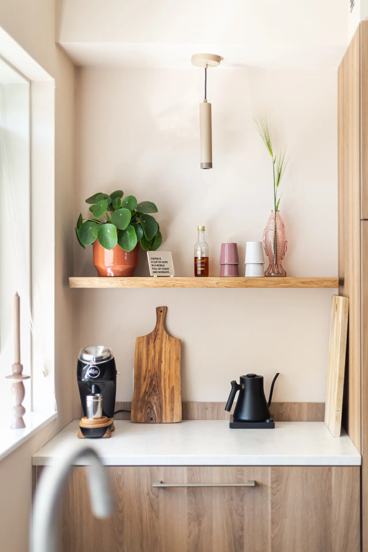 Keukennis met houten plank, koffiehoek en planten in een licht interieur in Zwolle