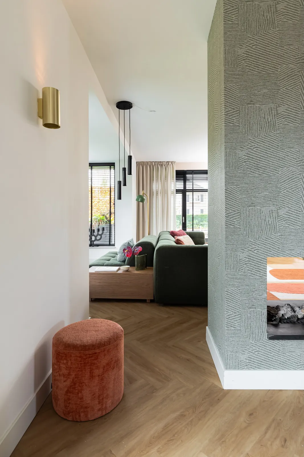 Doorkijk naar de woonkamer met oranje poef in een villa in Zwolle